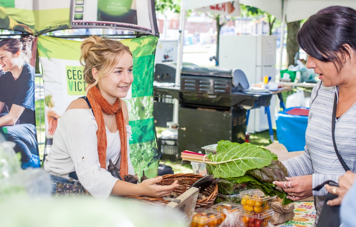Jeune femme faisant la vente des légumes de la ferme-école du Cégep de Victoriaville dans un kiosque extérieur