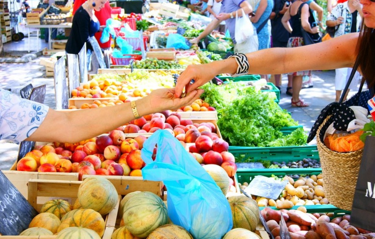 une personne donne de l'argent pour acheter légumes marché public