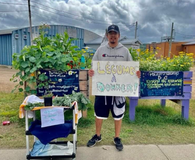Homme se tenant debout avec une pancarte légumes à donner